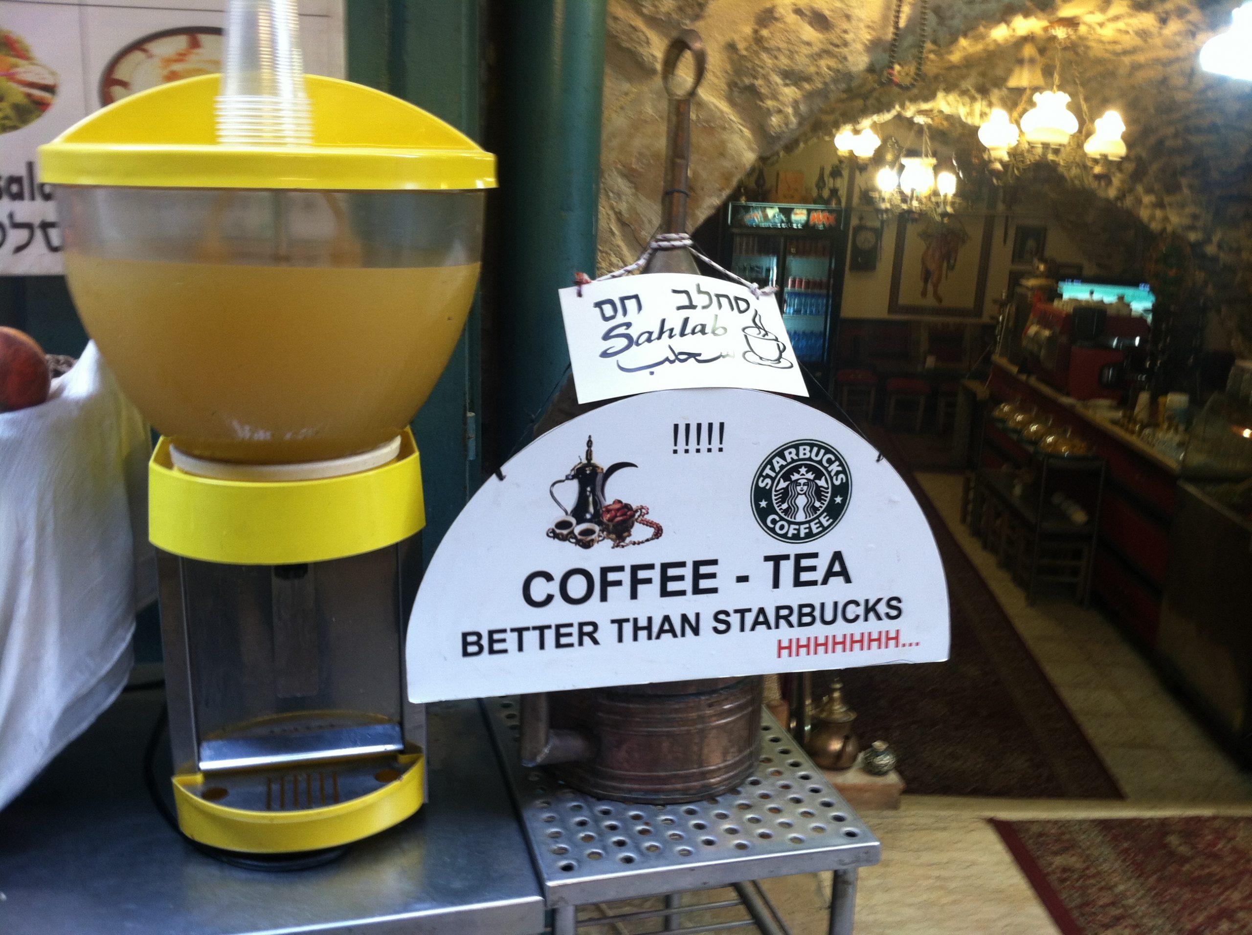 A sign at the entrance of a coffee shop insinuating that their coffee and tea better than Starbucks