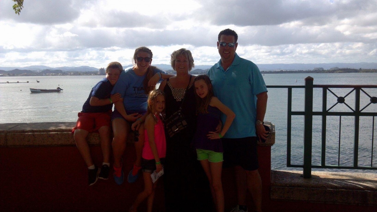 The Hayden family taking a group photo by a scenic waterfront
