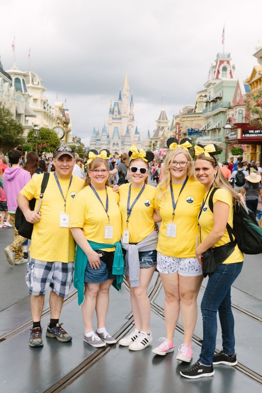 Judy and the Urlaub family smiling in front of Magic Kingdom in Orlando