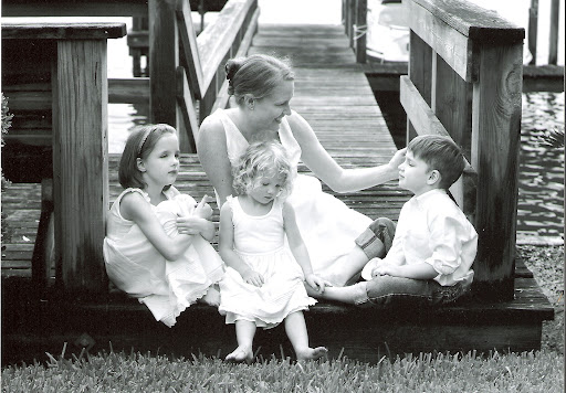 Inheritance of Hope Co-Founder, Kristen Milligan, with her three young children sitting on a dock wearing white. Kristen was intentional with her legacy and National Legacy Day™ is a day for everyone to do the same.