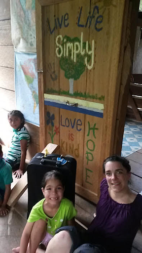 Woman and two children smiling while sitting in front of a decorated wooden door