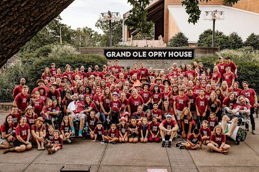 Large smiling group photo in front of the Grand Ole Opry House