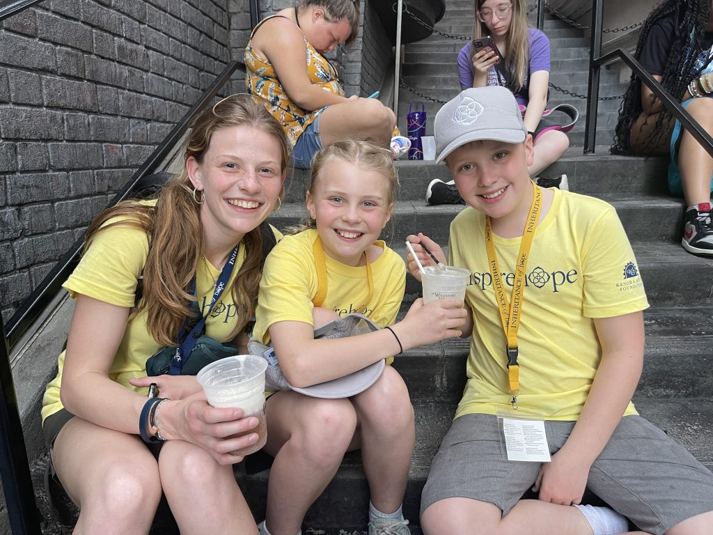 Two young girls and a young boy wearing yellow Inheritance of Hope shirts smiling.