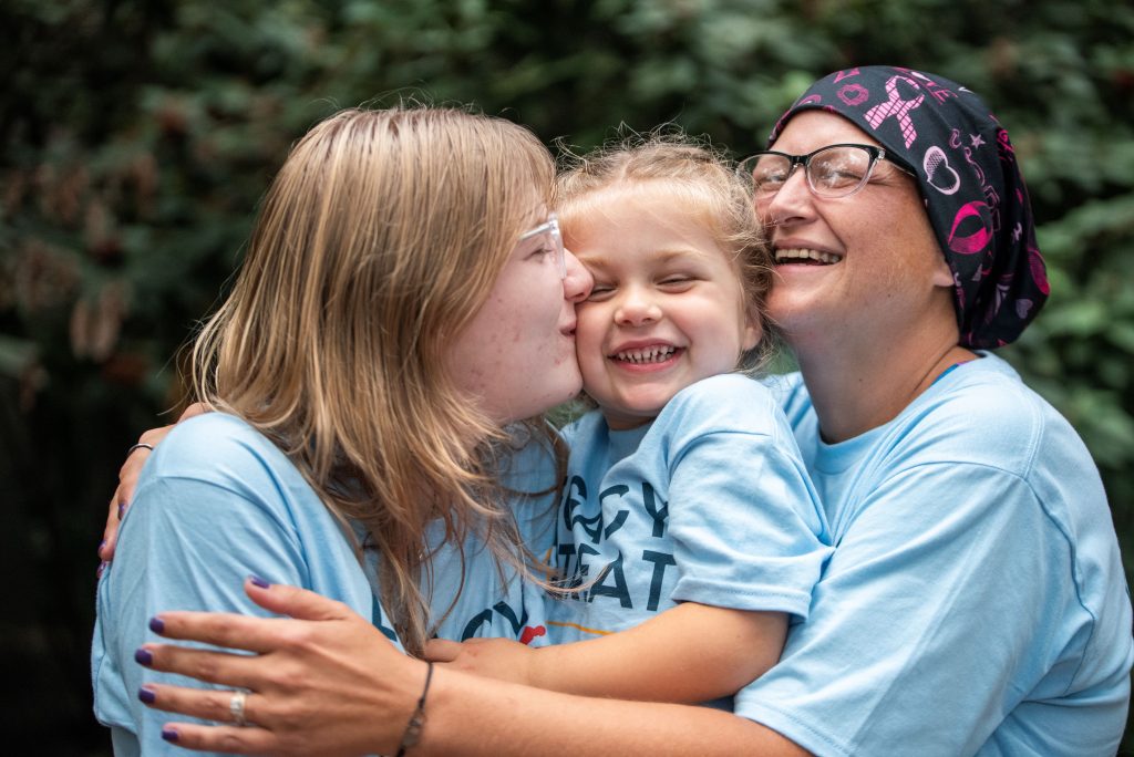 Mom with cancer hugging two daughters.