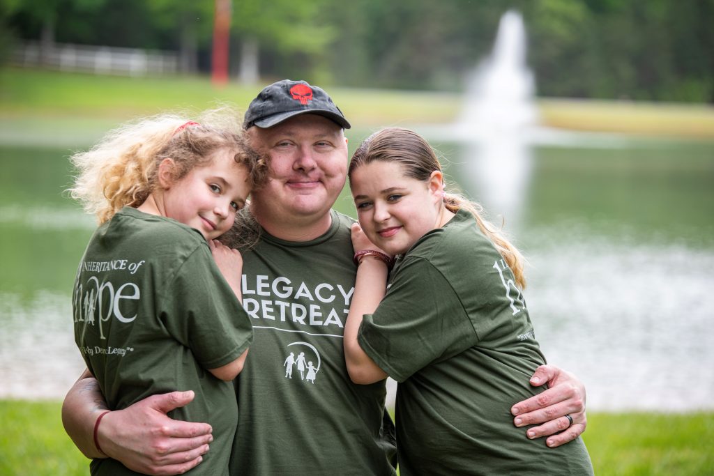 Photo of a dad with cancer hugging his two young daughters.
