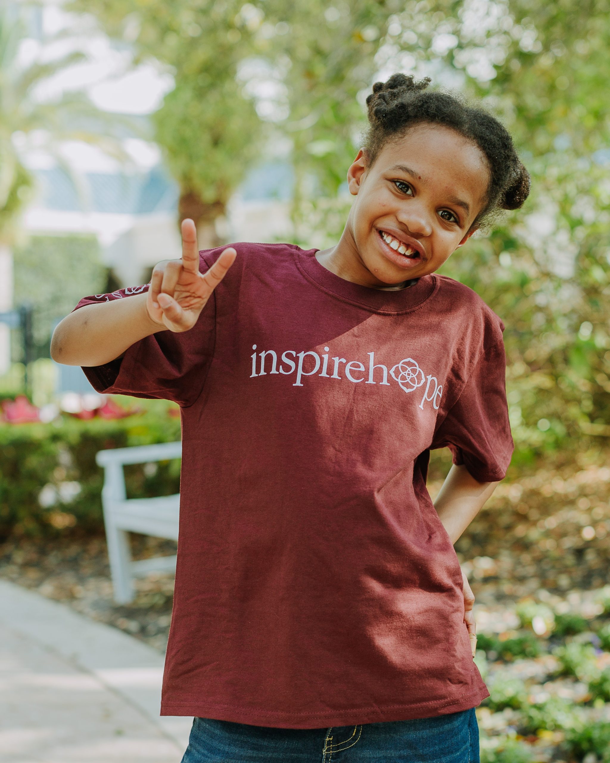 A smiling young girl holding up two fingers making a peace sign