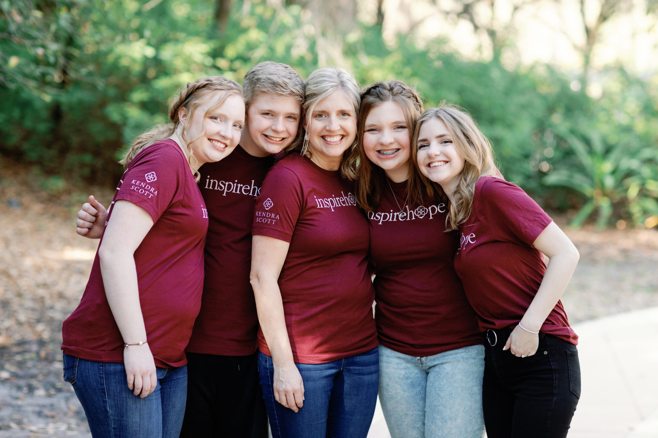 A photo of a woman surrounded by her 4 teenage children.