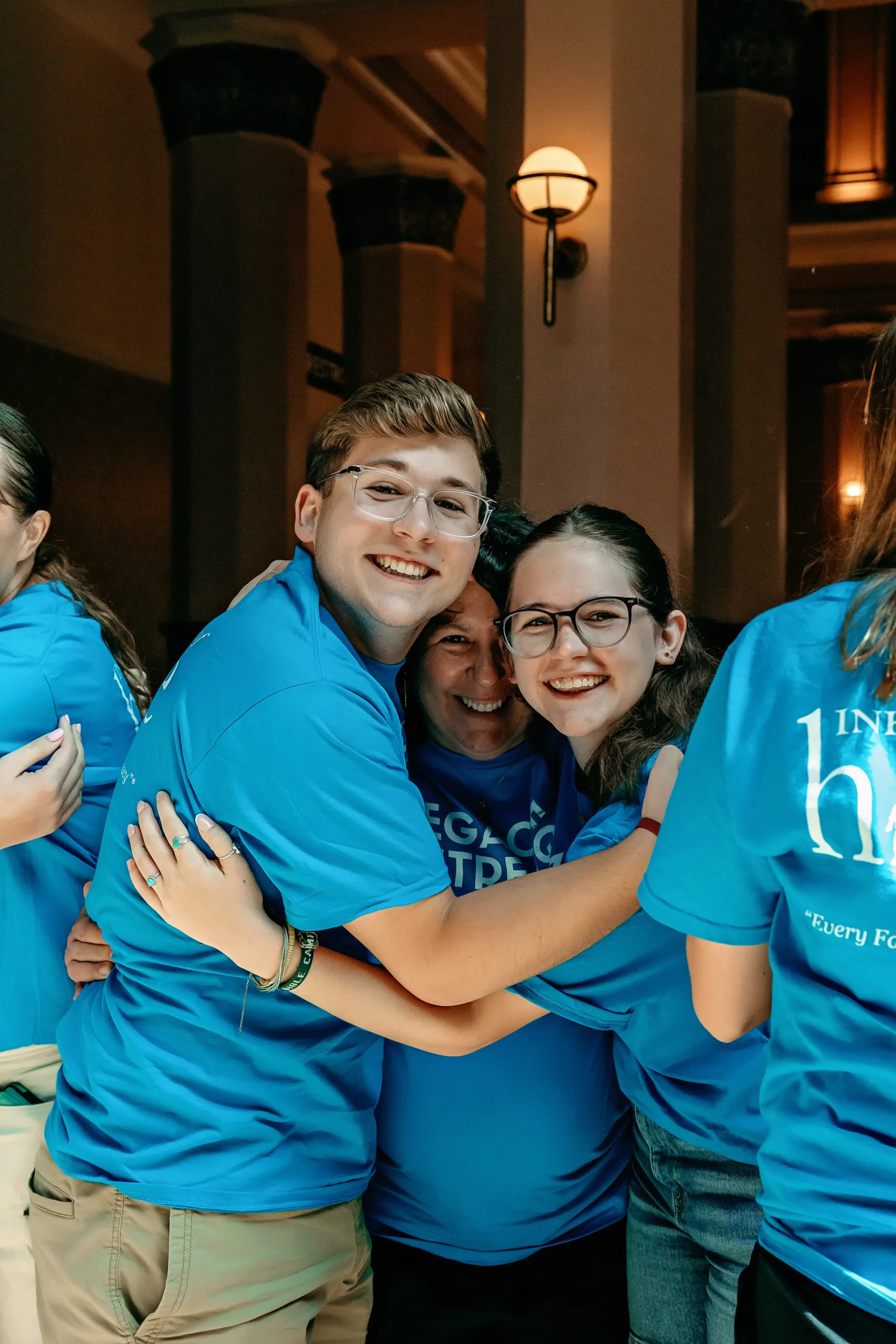 A family wearing blue Inheritance of hope t-shirts embracing each other and smiling