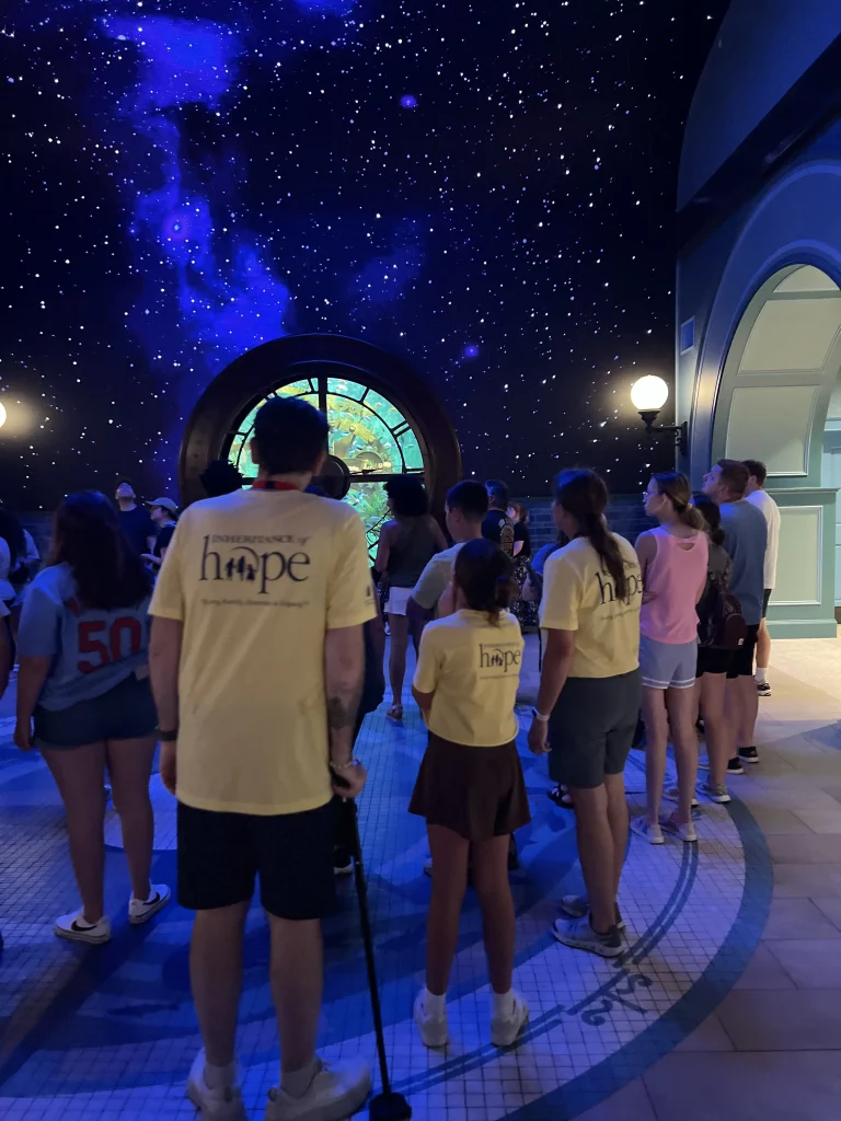 "Group of people in yellow Inheritance of Hope shirts looking at a starry display indoors.