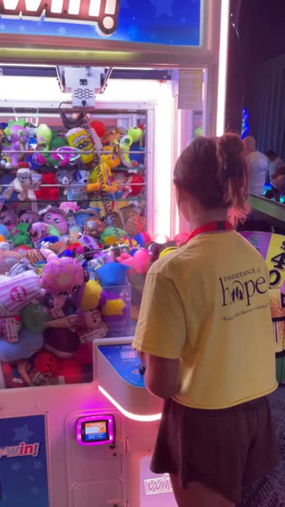 A girl using a claw machine at an arcade