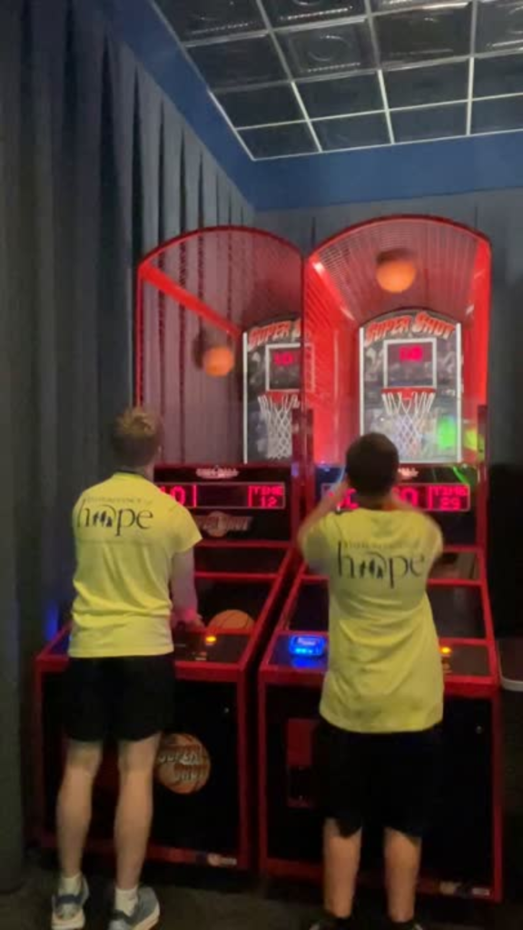 Two boys playing arcade basketball