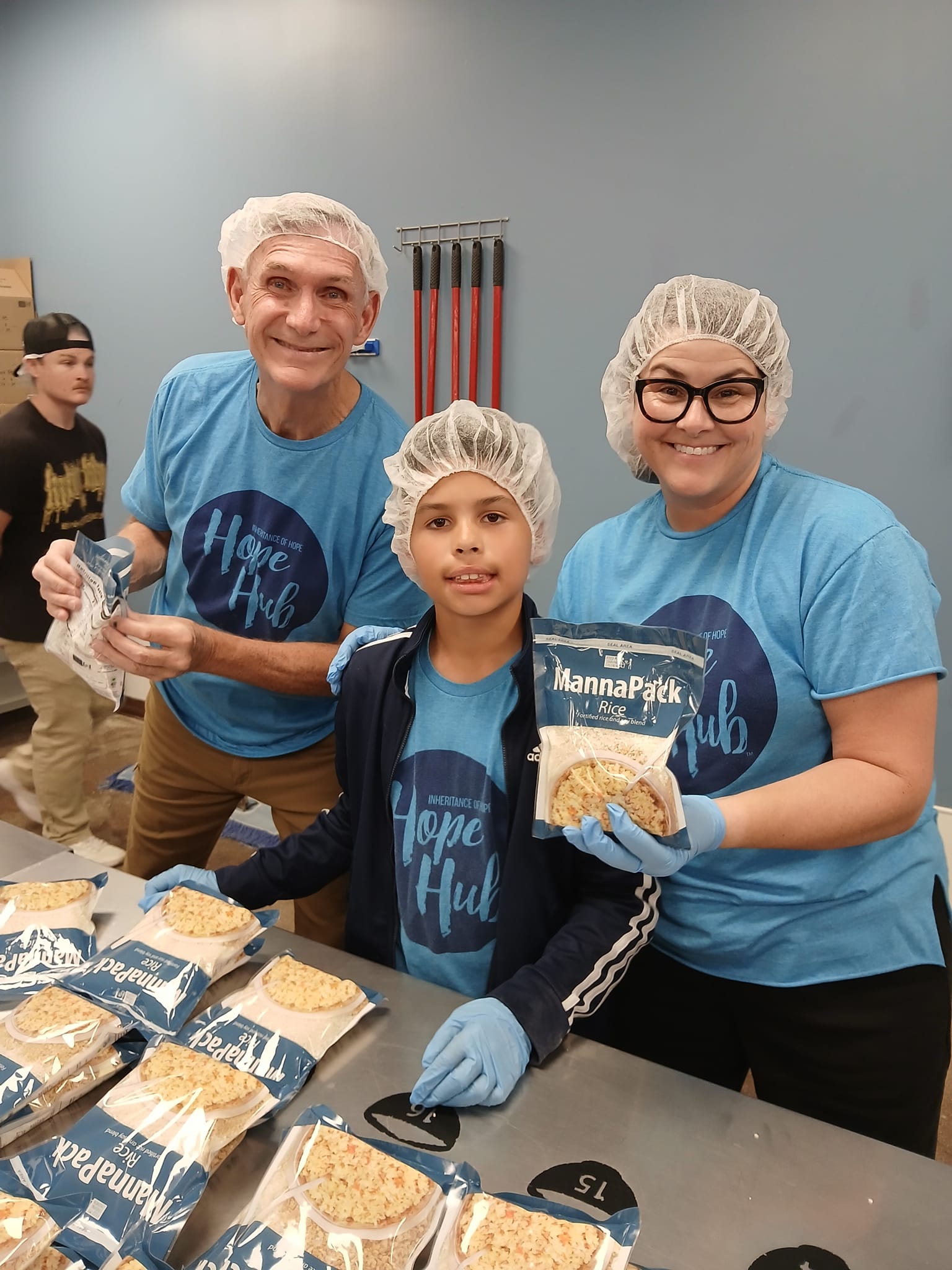 467331765_10160030161130964_971569404627446034_n A boy, a woman, and an older man doing volunteer work for a food drive