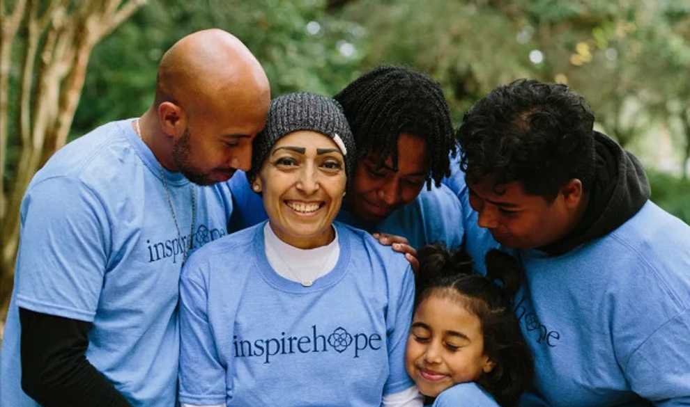 A mother being embraced by her husband and three children