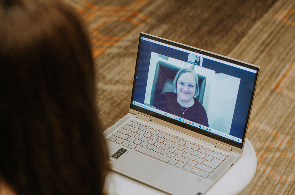 A woman sitting in from of a laptop on a video call with another woman