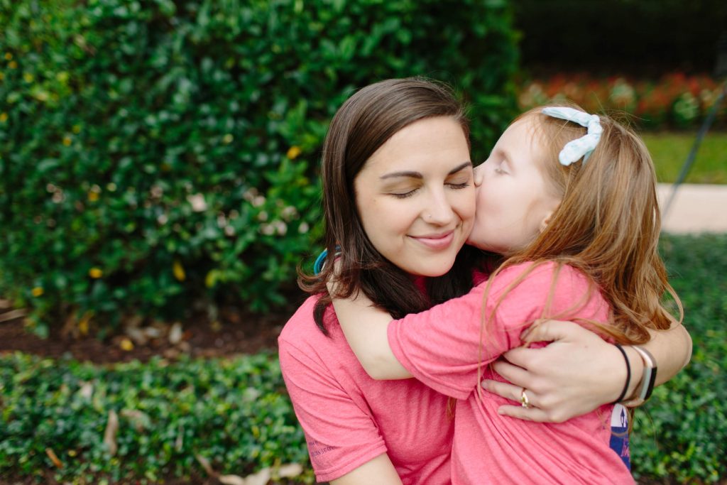 A young mom being kissed on the cheek by her daughter