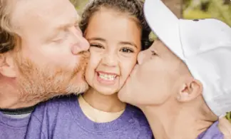 parents kissing smiling child