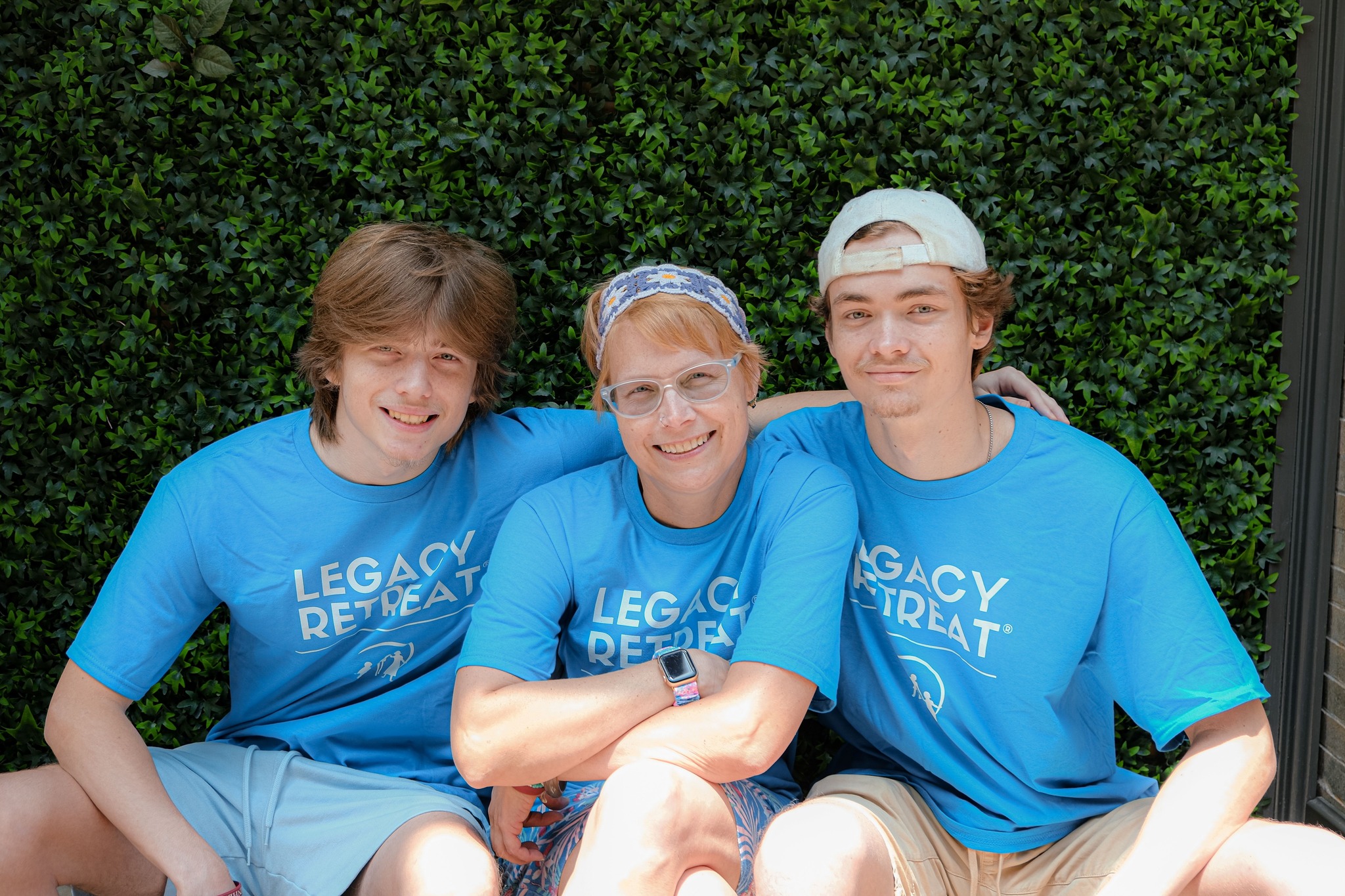 Three people in blue shirts smiling.