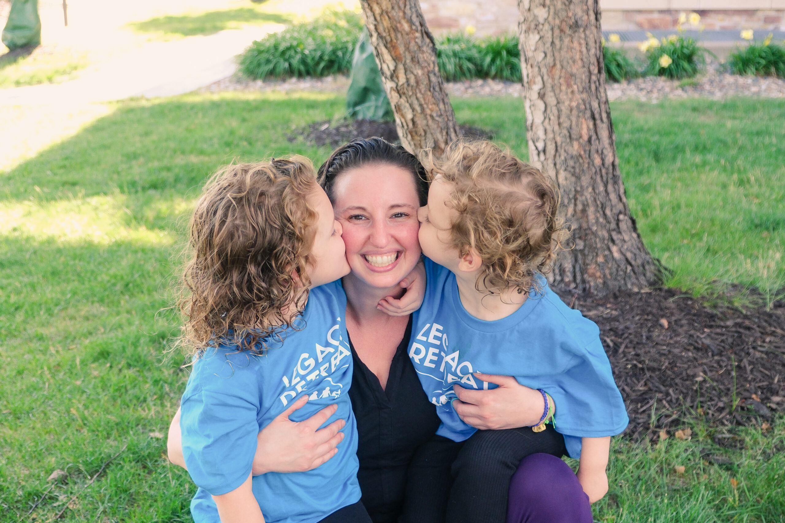 Two children kissing their mother on the cheek